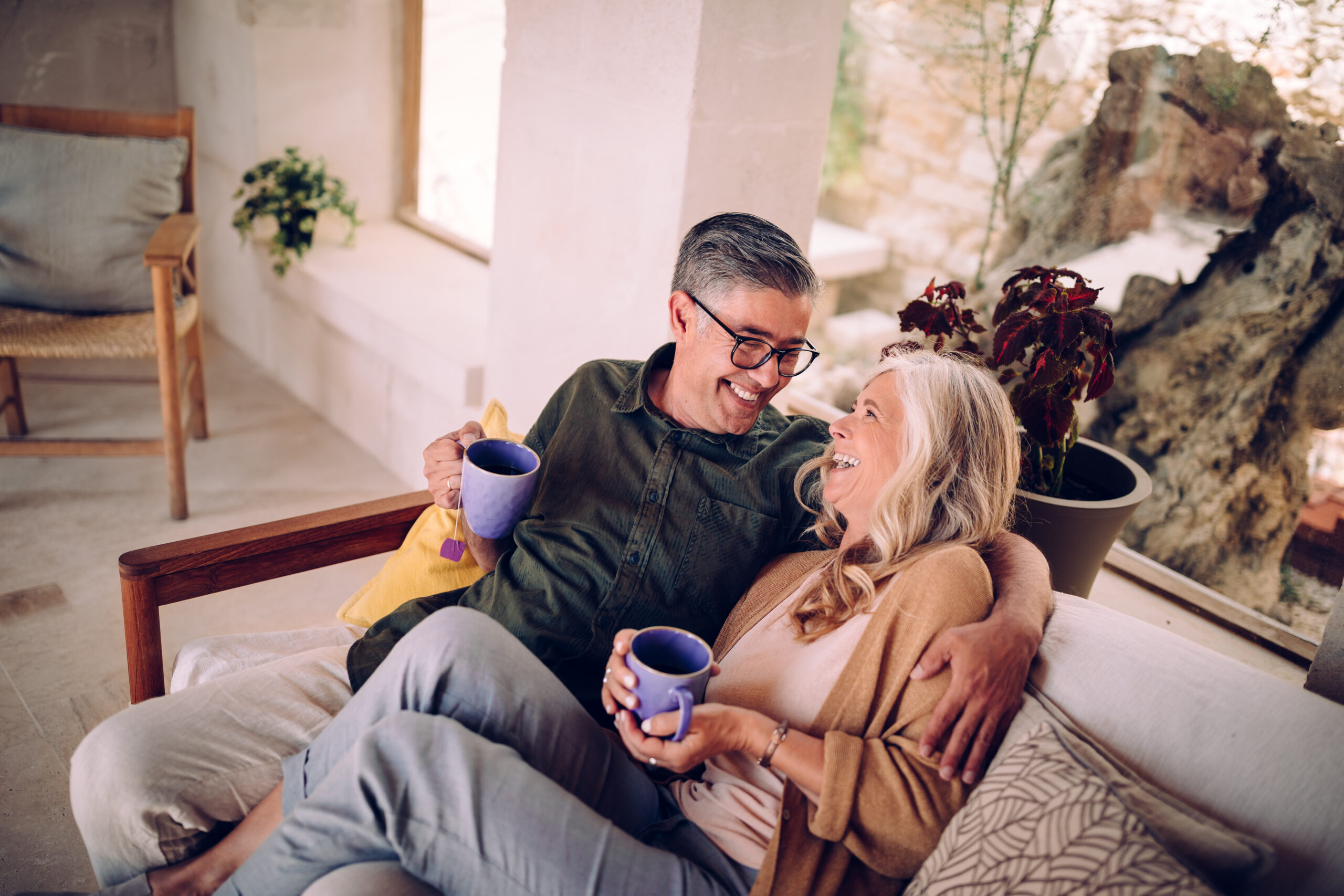 Senior couple drinking tea and laughing together at home